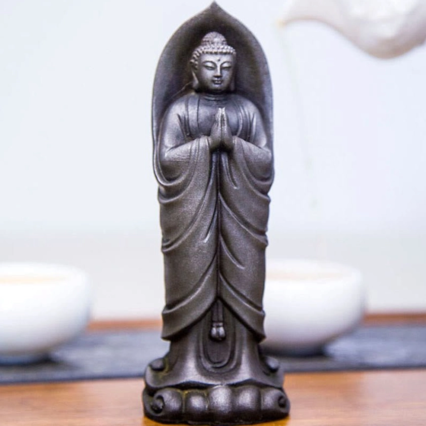 Buddhist Namaste Sakyamuni statue showing serene facial expression and prayer hands in spiritual meditation pose