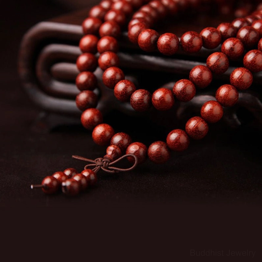Close-up side view of red sandalwood prayer beads showing wood grain texture and natural reddish-brown color