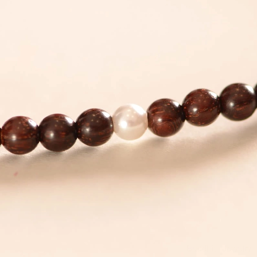 Close-up detail of red sandalwood beads and white pearl accent bead in Buddhist protection bracelet