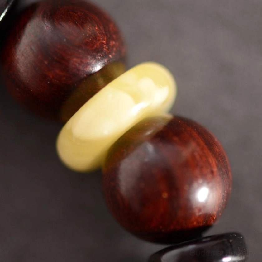 Close-up of light yellow agate spacer beads between dark red sandalwood round beads