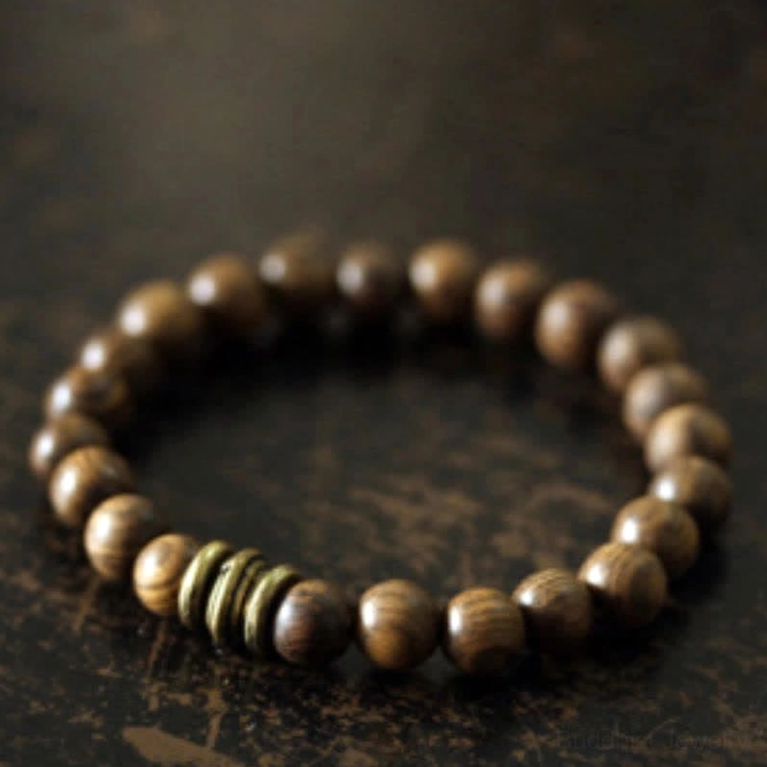 Handcrafted sandalwood meditation bracelet featuring polished round wooden beads and bronze accent rings, top angled view