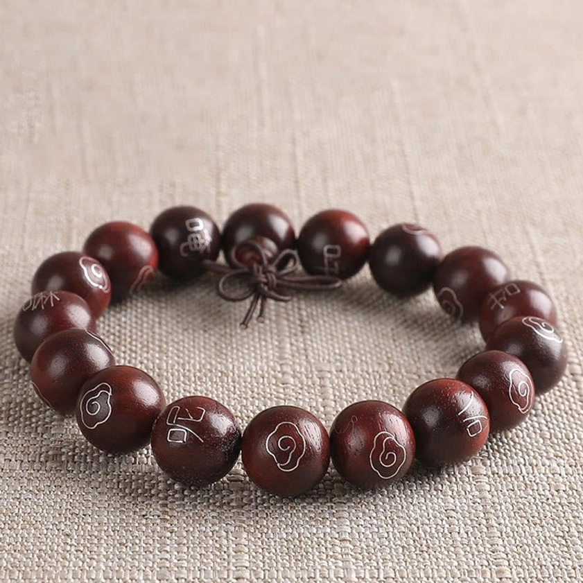 Close-up red sandalwood bracelet showing deep reddish-brown polished beads with clear sterling silver character inlays