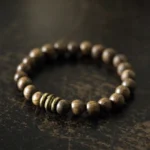 Sandalwood Buddhist protection bracelet with bronze metal spacers, three-quarter close-up view on dark vintage desktop