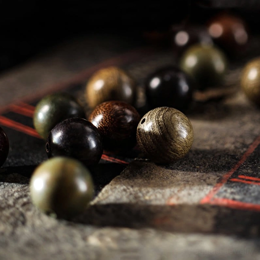 Mixed green and red sandalwood beaded bracelet with silver Buddha accent, angled view showing natural wood grain and color variations