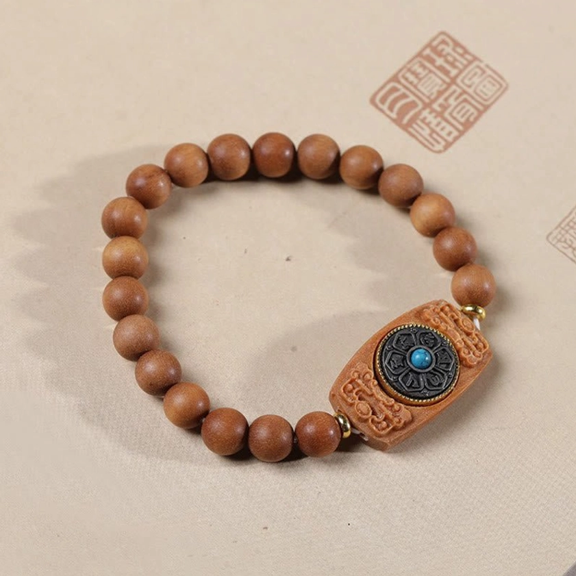 Sandalwood Buddhist bracelet with polished beads and engraved charm, overhead product photography