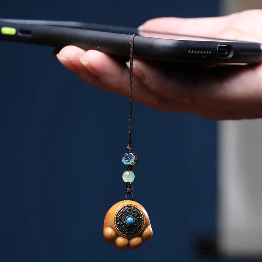 Real-life usage of tan sandalwood cat paw phone charm attached to mobile phone held in hand