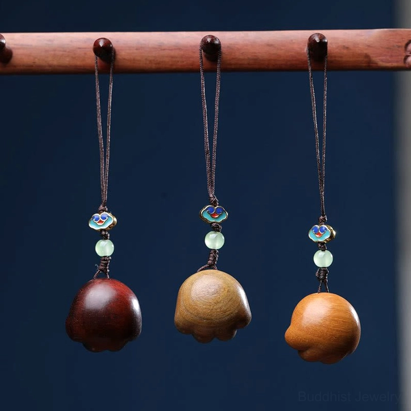 Three individual sandalwood cat paw charms in dark red, green, and tan wood showcasing natural color variations and material quality