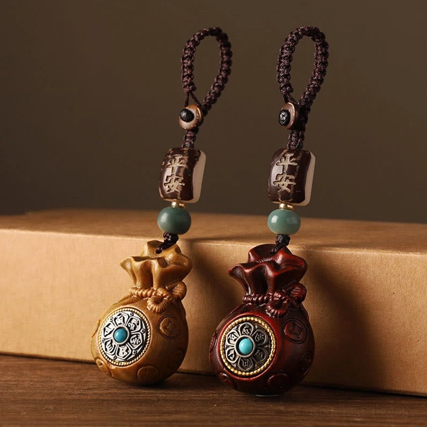 Handheld Buddhist money bag charm pendant showing size scale with protective peace bead attachment