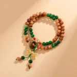 Sandalwood Dorje Vajra double twisted bracelet top view with brown wooden beads, green jade accents, and gold Dorje charm
