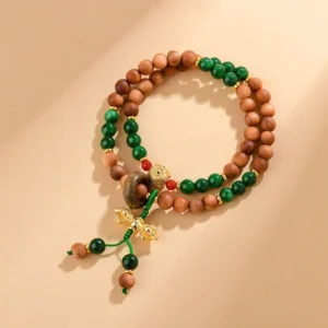 Sandalwood Dorje Vajra double twisted bracelet top view with brown wooden beads, green jade accents, and gold Dorje charm