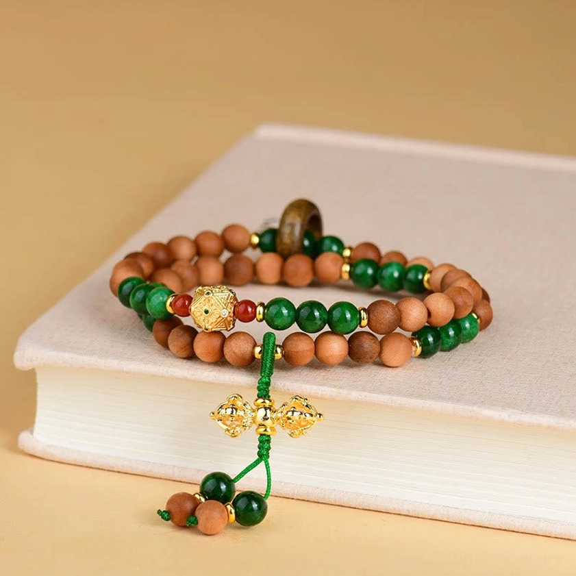 Sandalwood Dorje Vajra Buddhist bracelet side view on book with gold Dorje tassel and wooden spacer ring