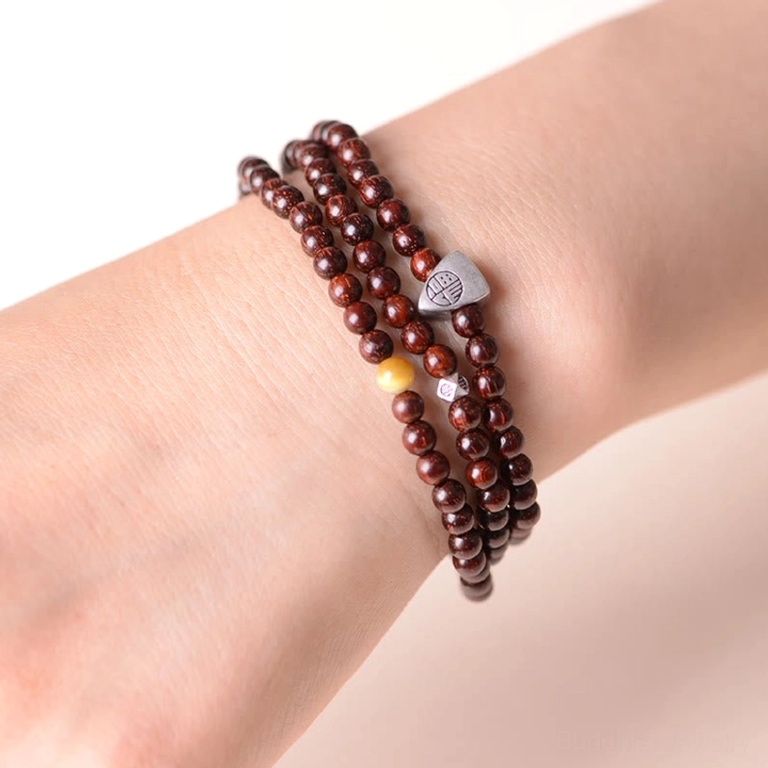 Red sandalwood Buddhist bracelet worn on side showing triple wrap design and silver Fu pendant