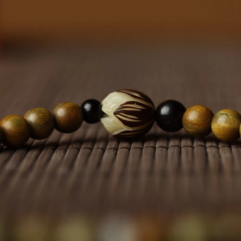 Extreme close-up detail of green sandalwood bracelet showing carved lotus bead with dark and light wooden bead texture