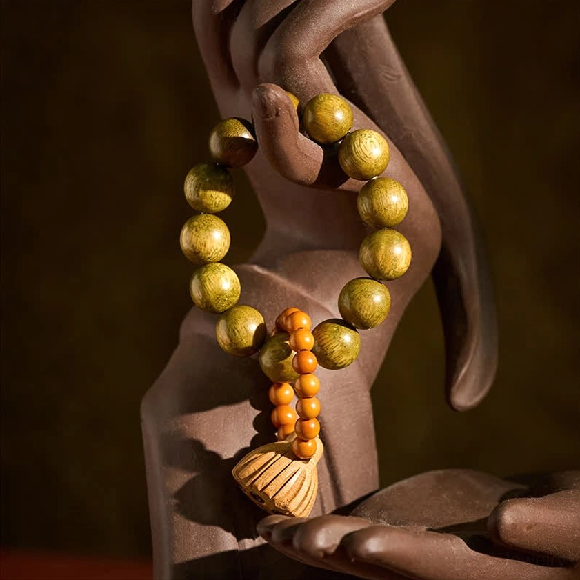 Sandalwood lotus meditation palm beads displayed on Buddha hand statue, showing yellowish-green polished beads with lotus pod pendant