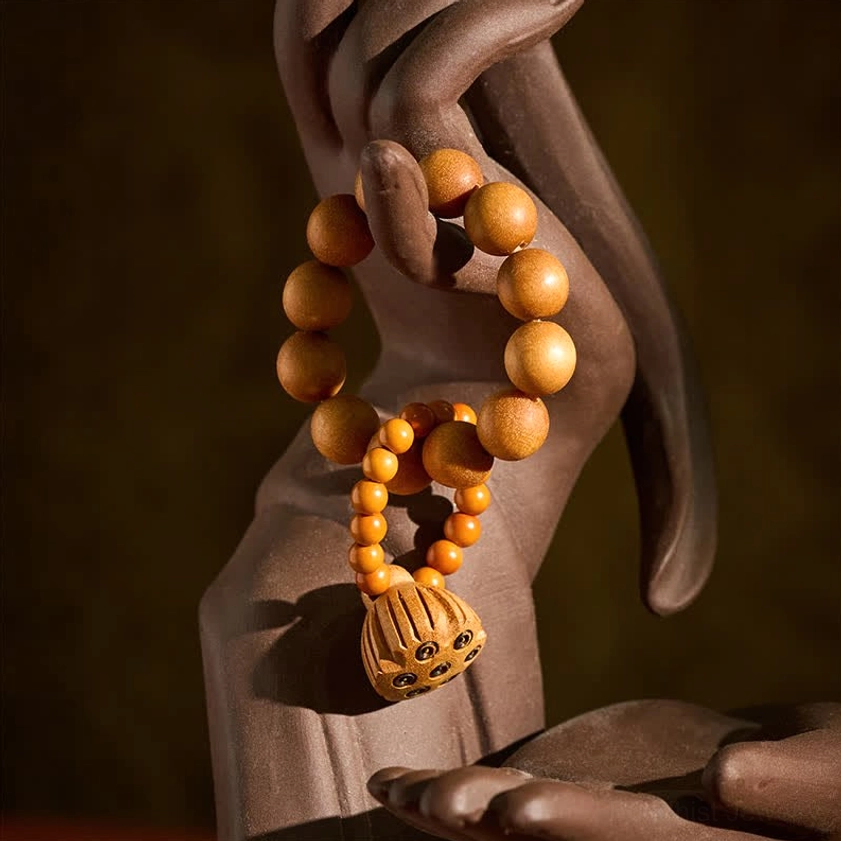 Sandalwood lotus meditation palm beads detail shot showing carved lotus pod pendant, smooth polished finish, and natural wood grain patterns