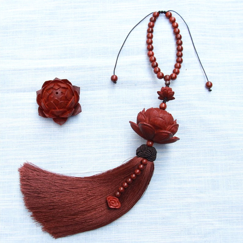 Red sandalwood lotus tassel decoration with loose carved lotus charm and beaded accents on blue background