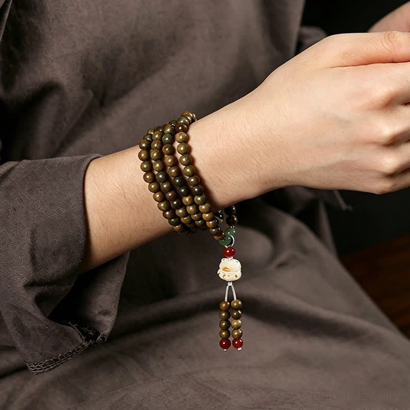Sandalwood mala bracelet worn on wrist in lifestyle close-up, showing cat-shaped tassel and natural wood patina