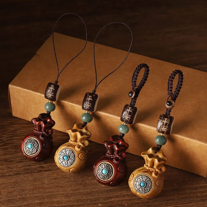 Multiple sandalwood Buddhist money bag charms in red and green color variants displayed together on kraft paper with matching protective beads
