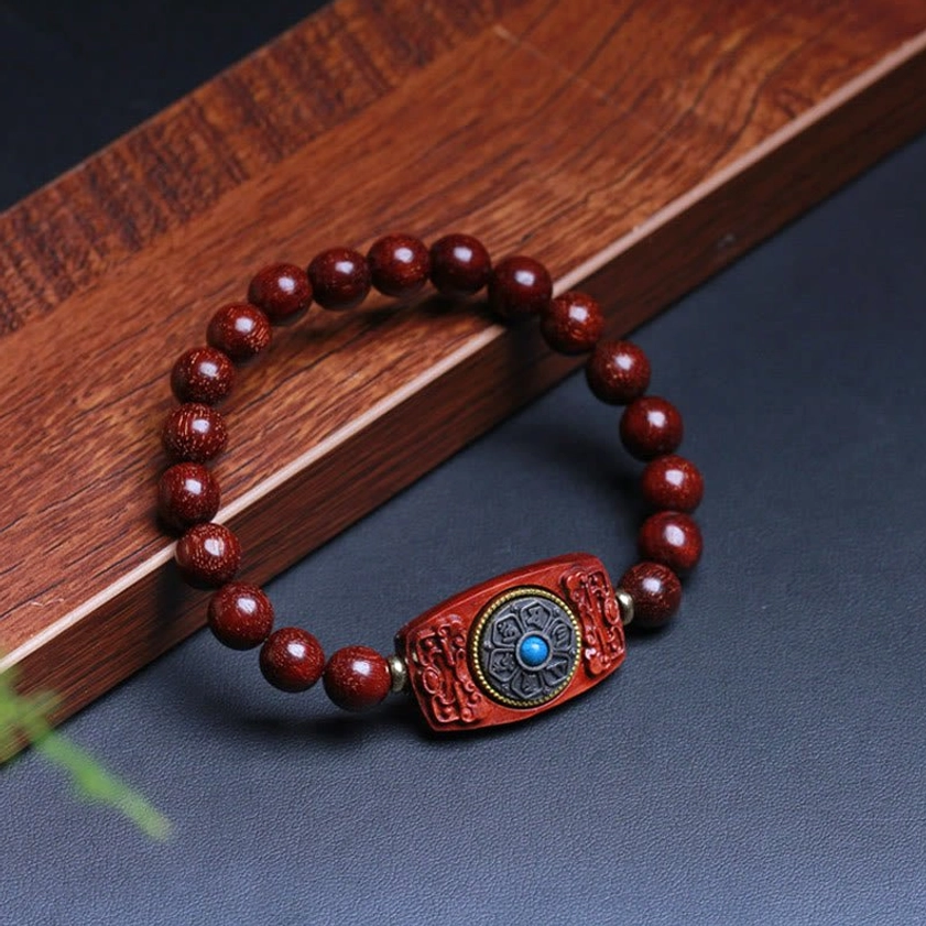 Red sandalwood peace bracelet with circular beads and focal charm featuring blue circular inlay, flat lay presentation