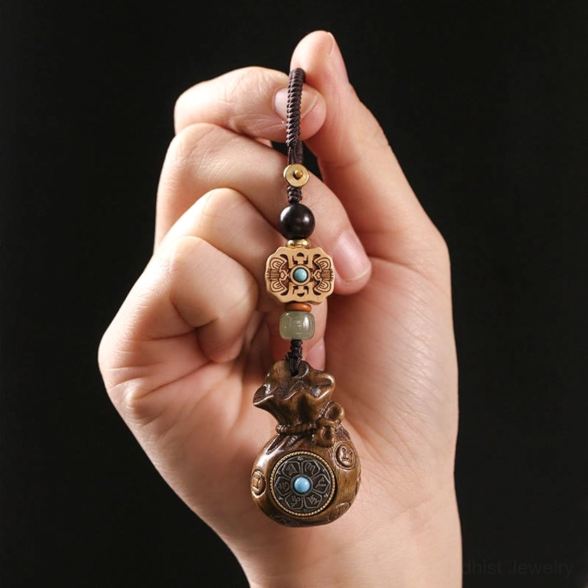 Sandalwood Om Mani Padme Hum charm held in hand showing carved details and natural wood grain close-up