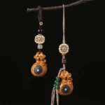 Sandalwood Om Mani Padme Hum keychain and phone charm with carved beads and turquoise inlay hanging on dark background
