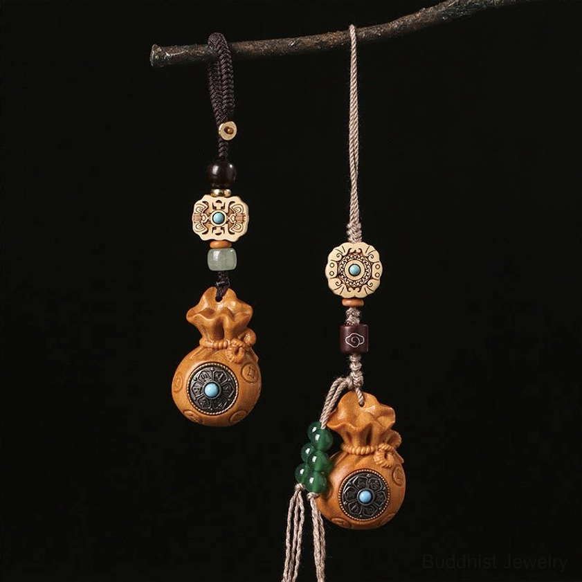 Sandalwood Om Mani Padme Hum keychain and phone charm with carved beads and turquoise inlay hanging on dark background