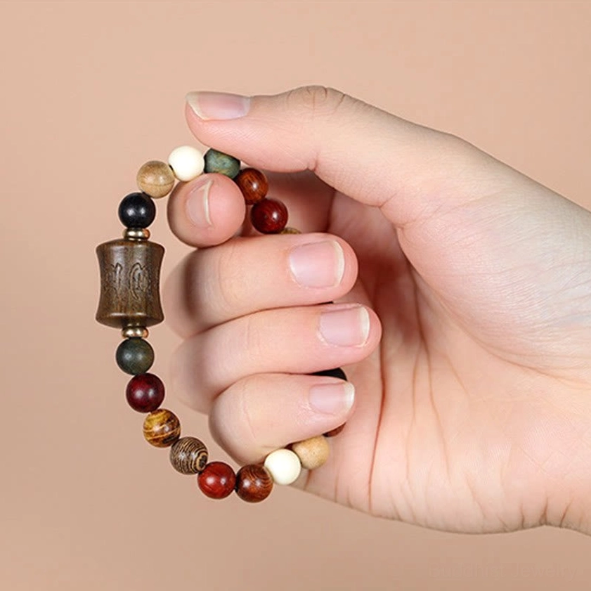 Sandalwood prayer bracelet held in hand displaying carved Om Mani Padme Hum mantra bead and natural wood colors