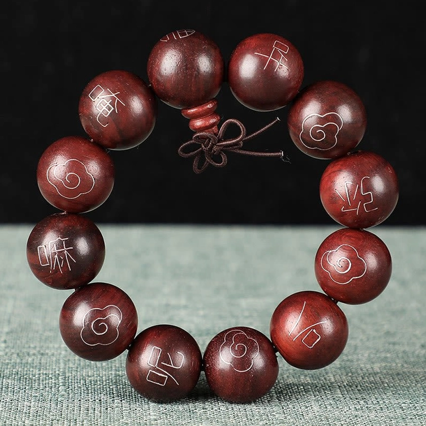 Red sandalwood Om Mani Padme Hum bracelet showing natural wood texture and intricate sterling silver character engravings