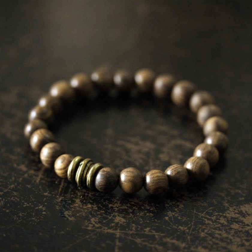 Smooth sandalwood meditation bracelet with wooden round beads and bronze metal spacer accents, angled close-up view