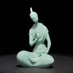Handcrafted sandstone Buddha statue with serene expression, seated in meditation pose, light green matte finish, front full-body view