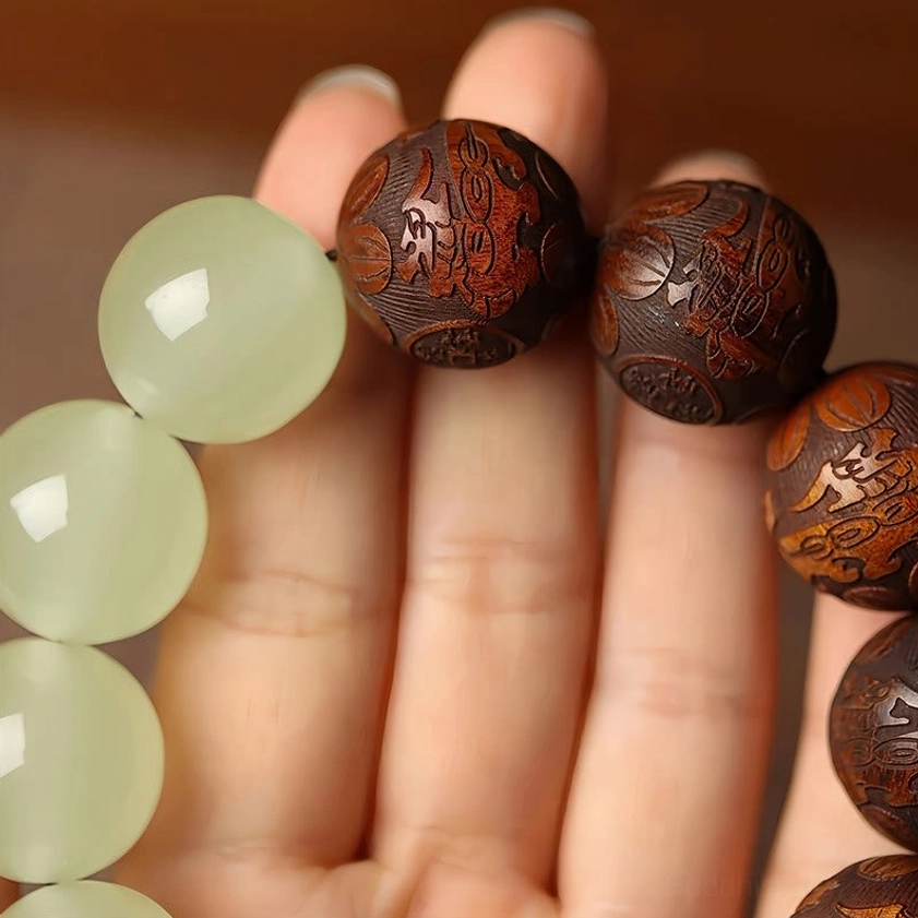 Close-up of intricately carved sappan wood and luminous jade beads on Buddhist protection bracelet