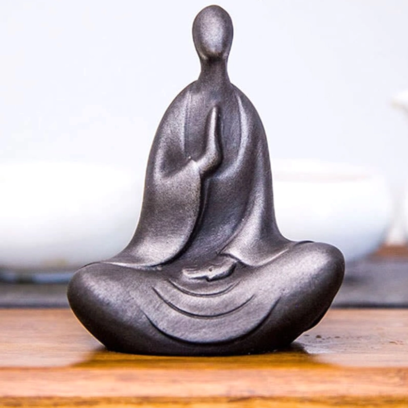 Seated Buddha desk decoration in dark matte gray with metallic sheen and detailed robe folds on wooden table