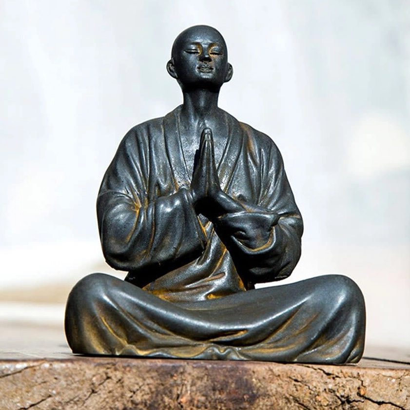 Seated Meditating Monk Statue Eye-Level View - Buddhist Spiritual Artwork on Weathered Wooden Table