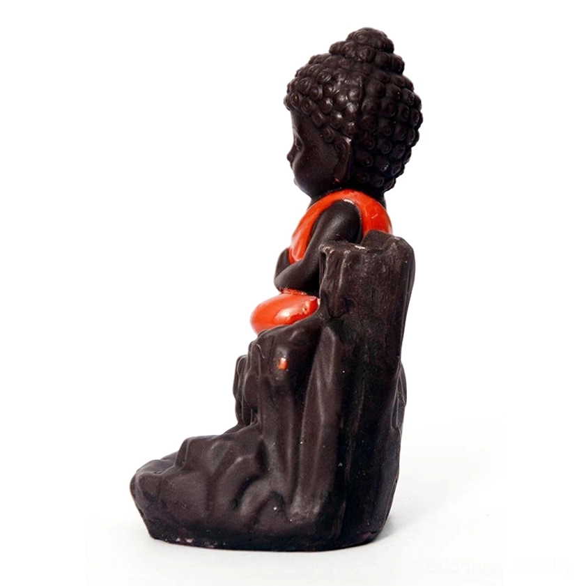 Side-rear perspective of seated monk ceramic incense holder on rock base with orange robe detail