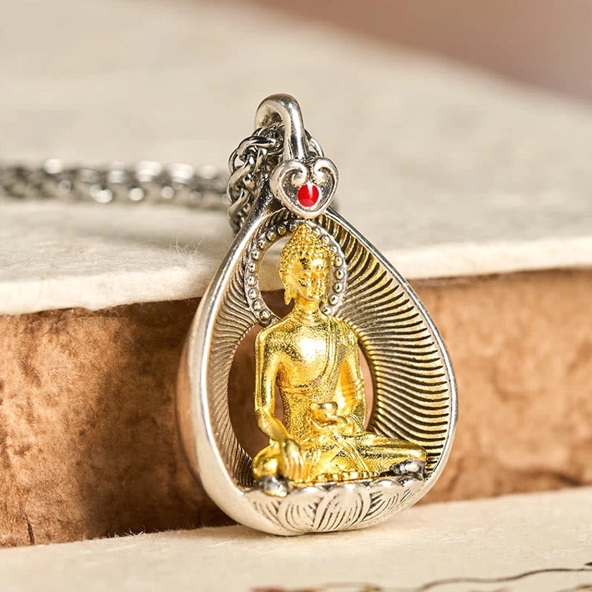 Shakyamuni Buddha copper pendant necklace three-quarter view on wooden surface showing enlightenment symbolism