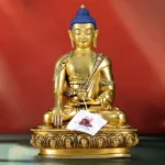 Shakyamuni Buddha earth-touching mudra copper statue front view with gilt bronze finish and blue curled hair, seated on lotus pedestal