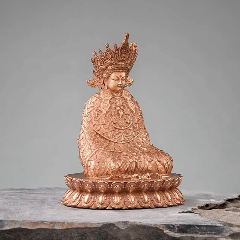 Seated Shakyamuni Buddha figurine showing detailed carved crown and intricately patterned robes from three-quarter front view on stone surface