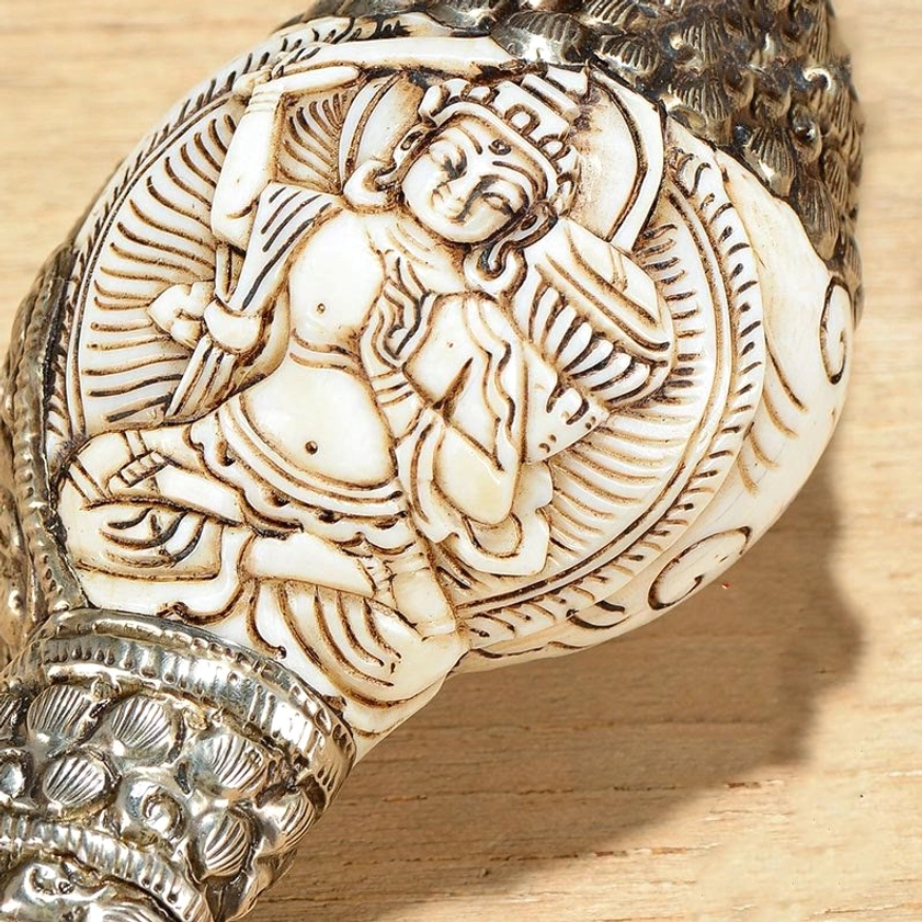 Close-up Buddha relief carving on shankha conch shell with silver frame