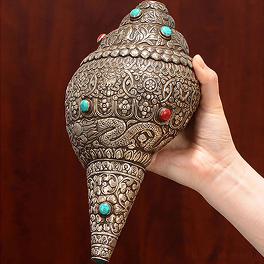 Handheld natural Shankha conch shell demonstrating carved auspicious symbols and silver plating details
