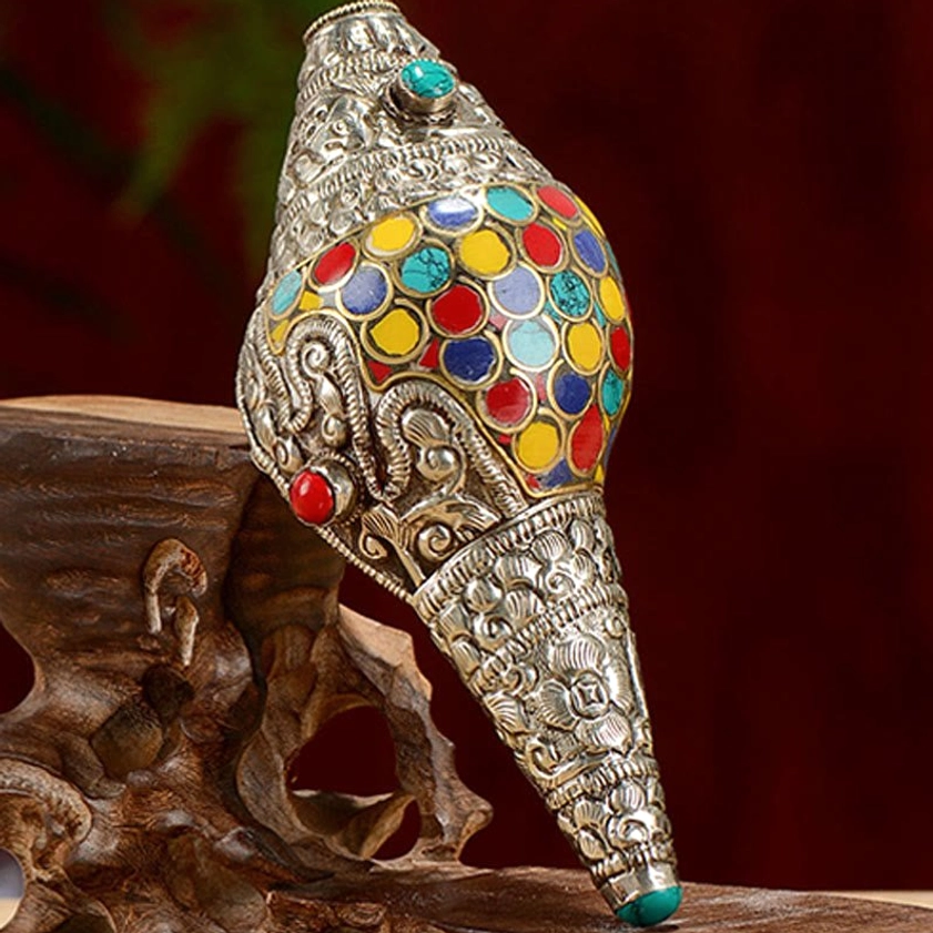 Oblique view of handcrafted shankha ornament displaying colorful enamel work and red turquoise gemstone details