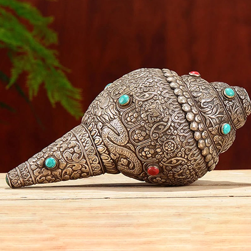 Side view of Shankha conch shell with delicate embossed patterns, turquoise and red gemstone accents