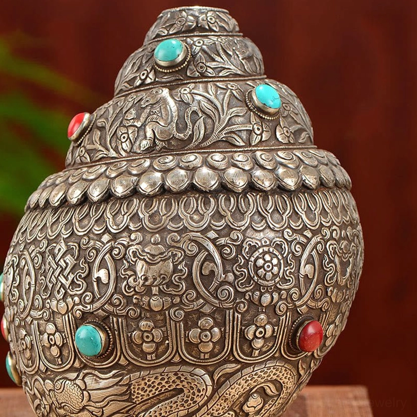 Upper section of Shankha conch shell featuring layered carved patterns, floral reliefs, and turquoise gemstone settings