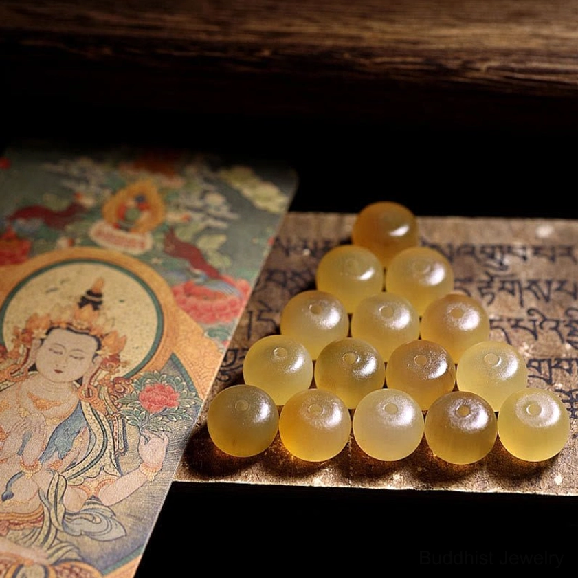 Loose natural sheep horn beads and components for Buddhist bracelet with warm yellow translucent tone arranged with Tibetan scripture background