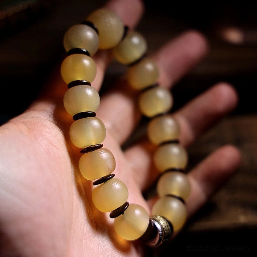 Handmade Buddhist sheep horn bracelet held in palm of hand showing natural texture and metal clasp, wearable view with dark spacer rings