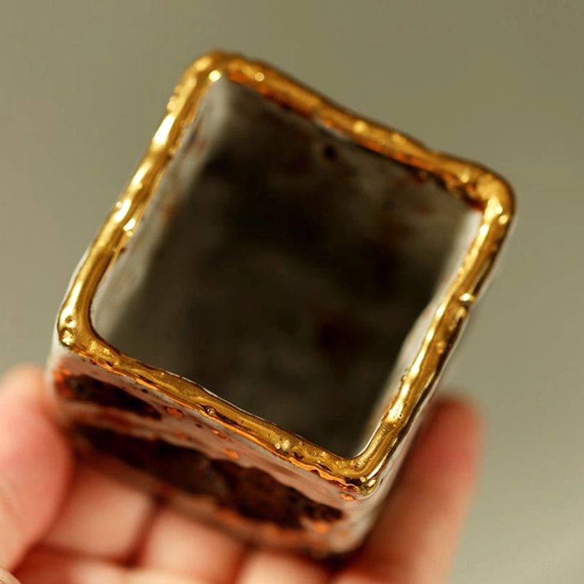 Interior view of Buddhist ceramic tea cup showing gilded rim and dark unglazed interior with rough pottery texture