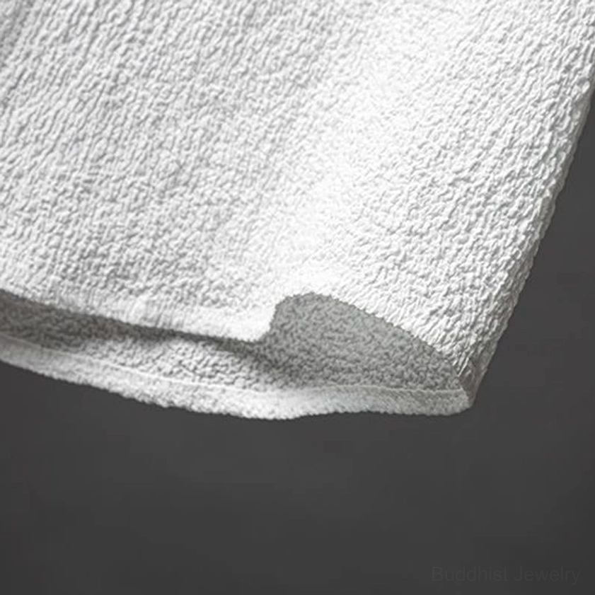 Extreme close-up of white shirt fabric texture and single black button placket, showing polyester blend material