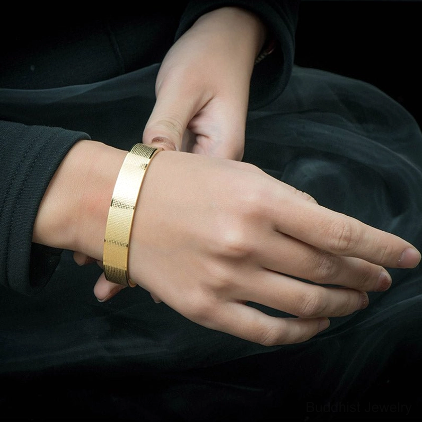 Shurangama Mantra titanium steel bracelet worn on wrist showing polished gold finish and adjustable open design