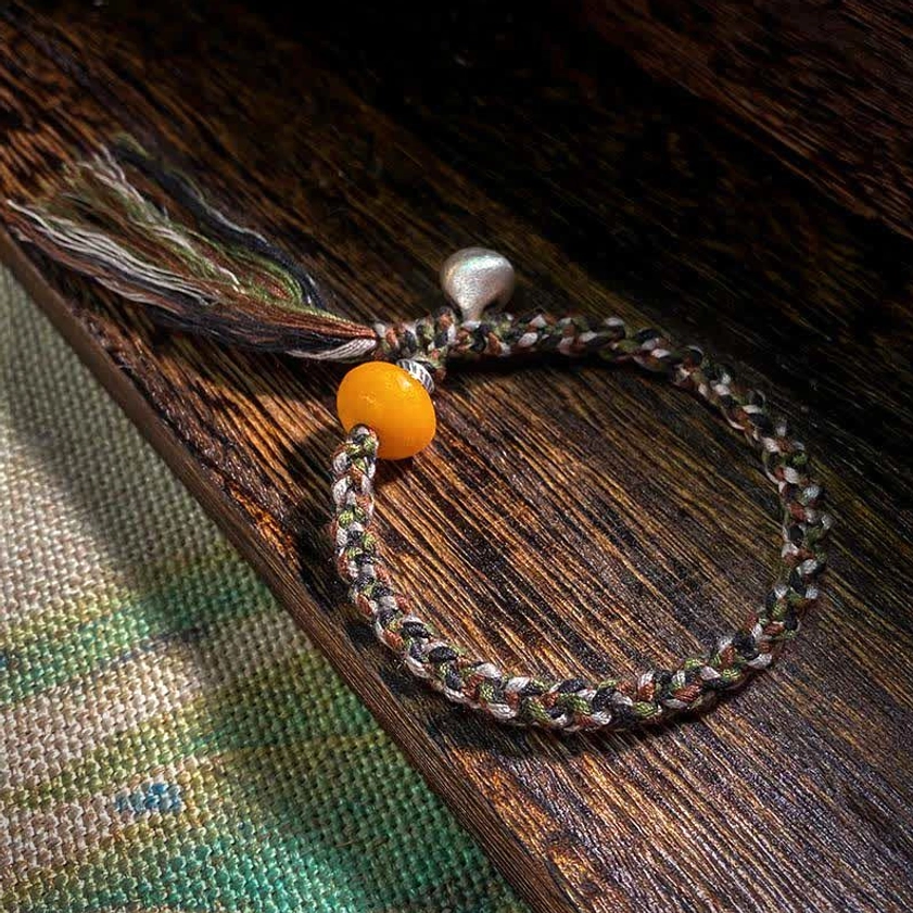 Handmade 990 sterling silver amber steelyard weight bracelet with protective charm on wooden surface and woven fabric