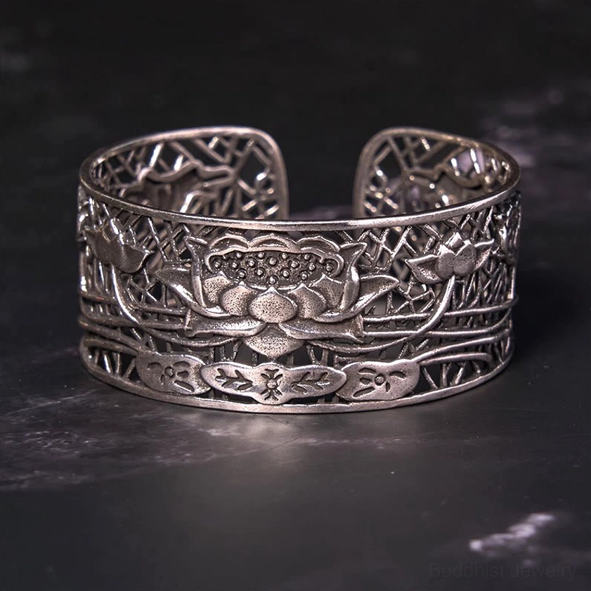 Close-up front view of silver lotus carved cuff bracelet featuring detailed hollowed lotus and leaf relief patterns on dark textured background