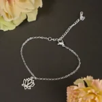 Silver lotus titanium steel bracelet flat lay with delicate cable chain and hollow lotus pendant charm